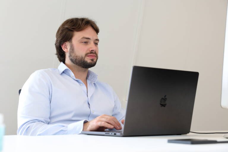 man zit aan tafel aan het werk achter zijn laptop, kijkend naar zijn B2B-leads