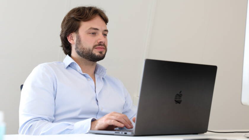 man zit aan tafel aan het werk achter zijn laptop, kijkend naar zijn B2B-leads