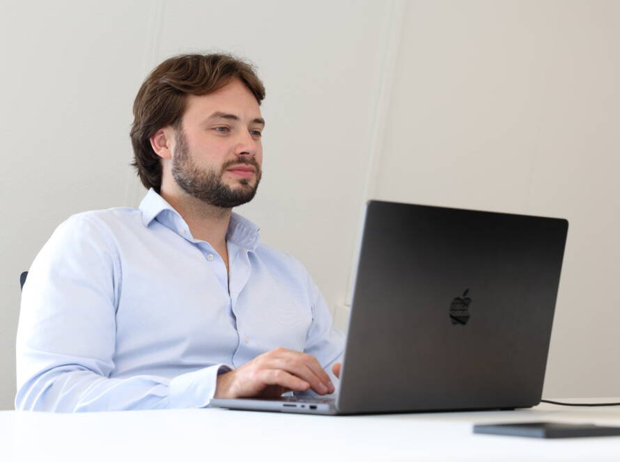 man zit aan tafel aan het werk achter zijn laptop, kijkend naar zijn B2B-leads