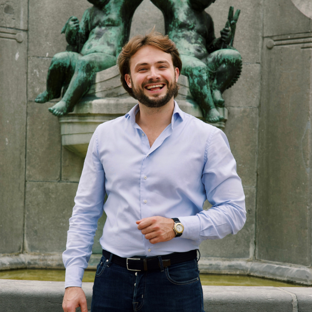 Foto van lachende man met achter hem een standbeeld