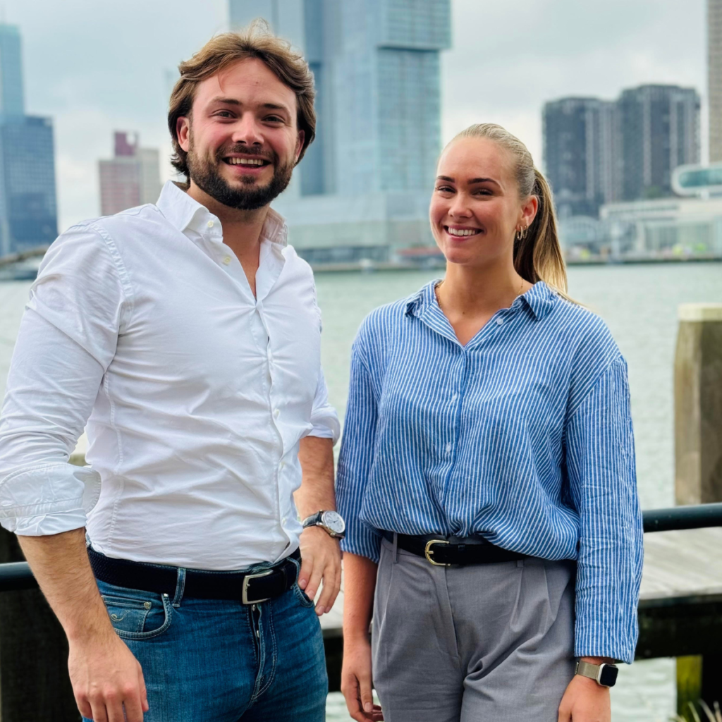 Man en vrouw werkzaam bij de growth agency van rotterdam lachend met skyline van Rotterdam op de achtergrond