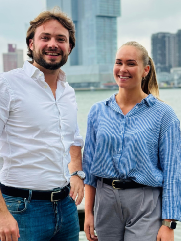 Man en vrouw werkzaam bij de digital growth agency van rotterdam lachend met skyline van Rotterdam op de achtergrond
