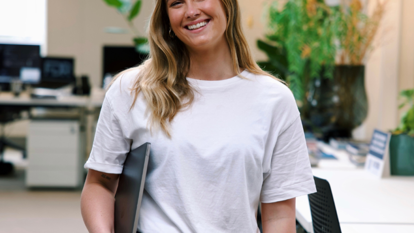 Vrouw lachend op kantoor met laptop in rechterhand