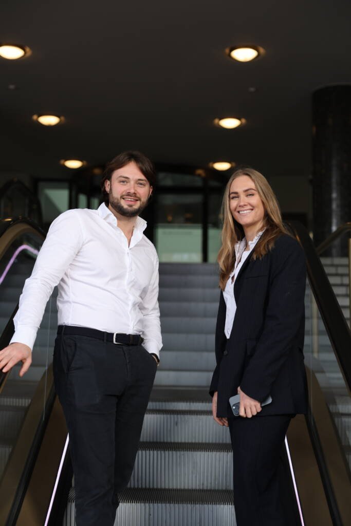 Man en vrouw lachend kijken naar camera terwijl ze omhoog gaan op roltrap
