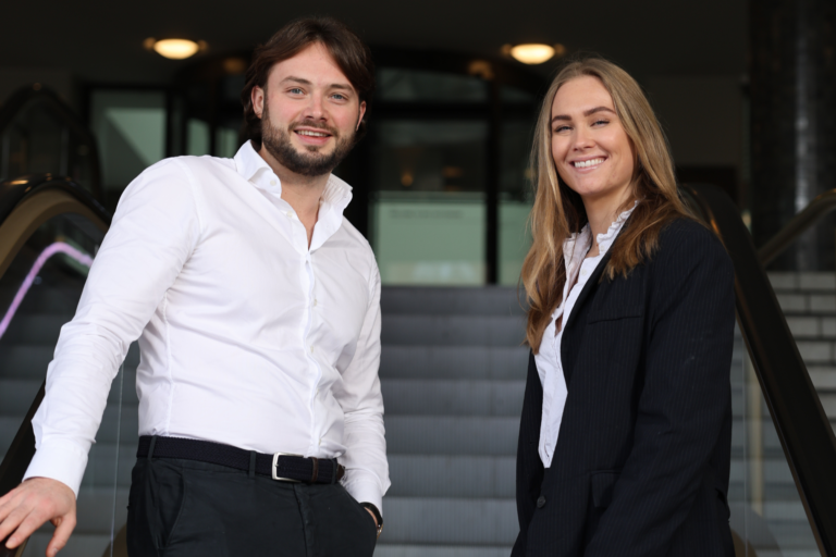 Man en vrouw lachend kijken naar camera terwijl ze omhoog gaan op roltrapMan en vrouw lachend kijken naar camera terwijl ze omhoog gaan op roltrap