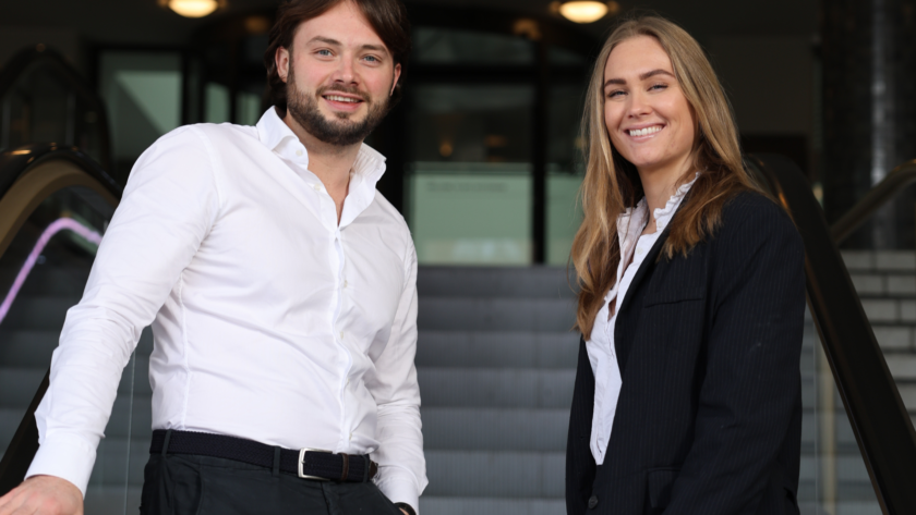 Man en vrouw lachend kijken naar camera terwijl ze omhoog gaan op roltrapMan en vrouw lachend kijken naar camera terwijl ze omhoog gaan op roltrap